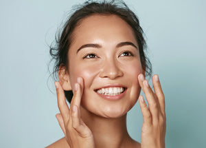 Close up of a smiling ladies face applying skincare on her cheeks