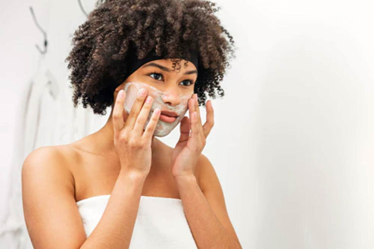 lady in a towel in her bathroom applying skincare on her face