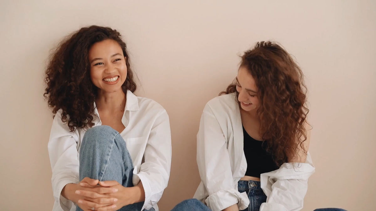 Two women in white shirts, laughing
